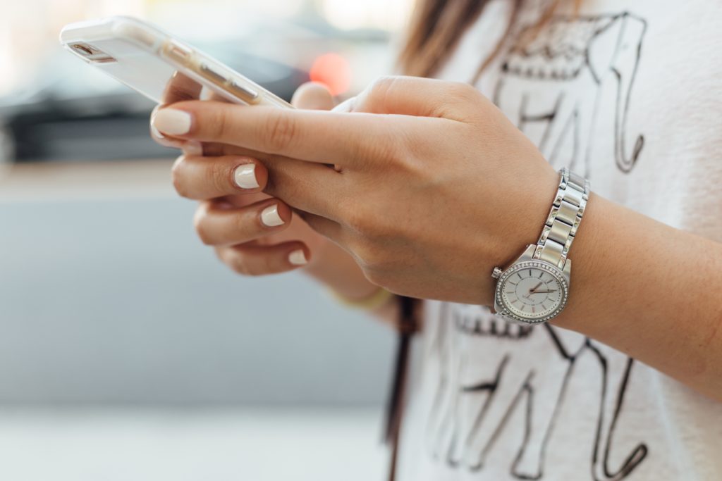 Woman's hands holding a cell phone and texting, which could be part of a casual dating affair.
