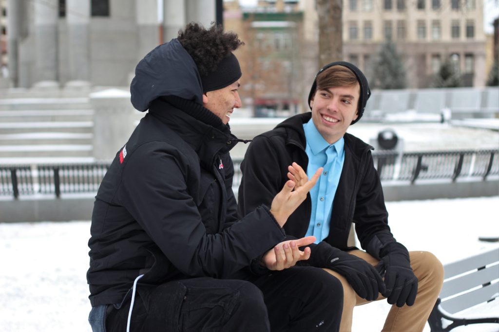 Two men in coats sitting on a park bench and talking