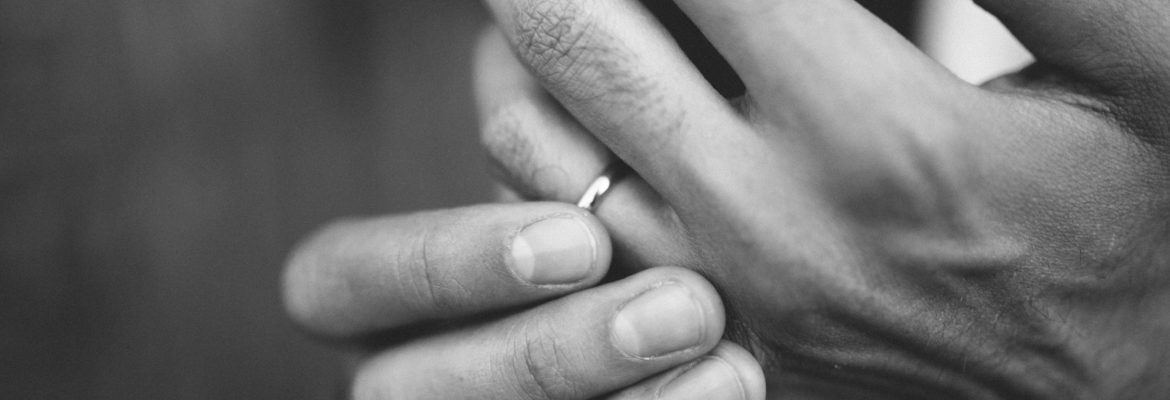 Image shows man's hands, fingering his wedding ring