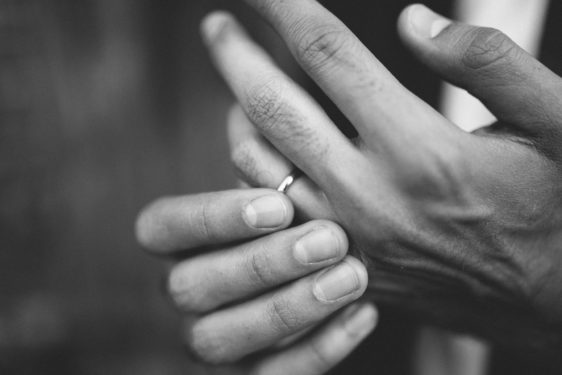 Image shows man's hands, fingering his wedding ring